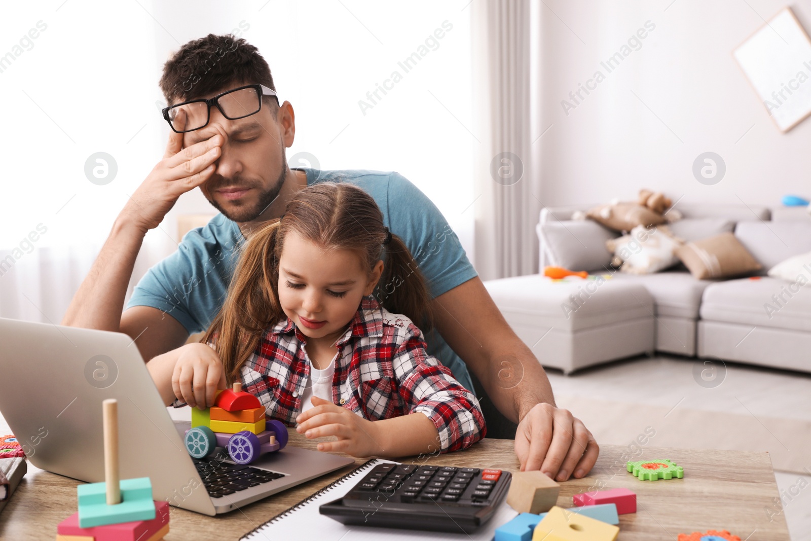 Photo of Cute child disturbing stressed man in living room. Working from home during quarantine