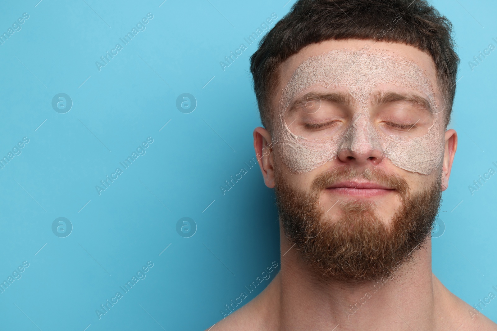 Photo of Handsome man with facial mask on his face against light blue background, space for text