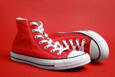 Pair of new stylish sneakers on red background