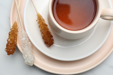 Sticks with sugar crystals served to tea on white marble table, top view