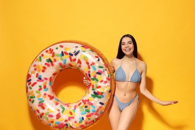 Young woman with inflatable ring against orange background