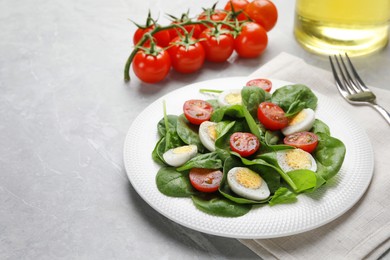 Delicious salad with boiled eggs, tomatoes and spinach on light grey table