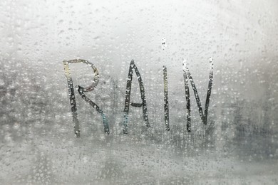 Photo of Word Rain written on foggy window, closeup view