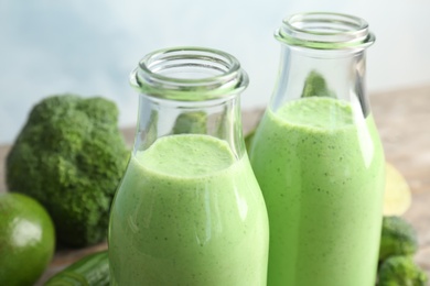 Photo of Bottles with healthy detox smoothie on table, closeup