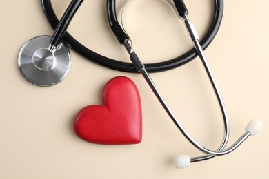 Photo of Stethoscope and red heart on beige background, top view
