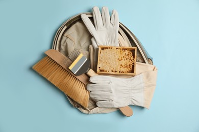 Photo of Beekeeping tools and uniform on light blue background, top view