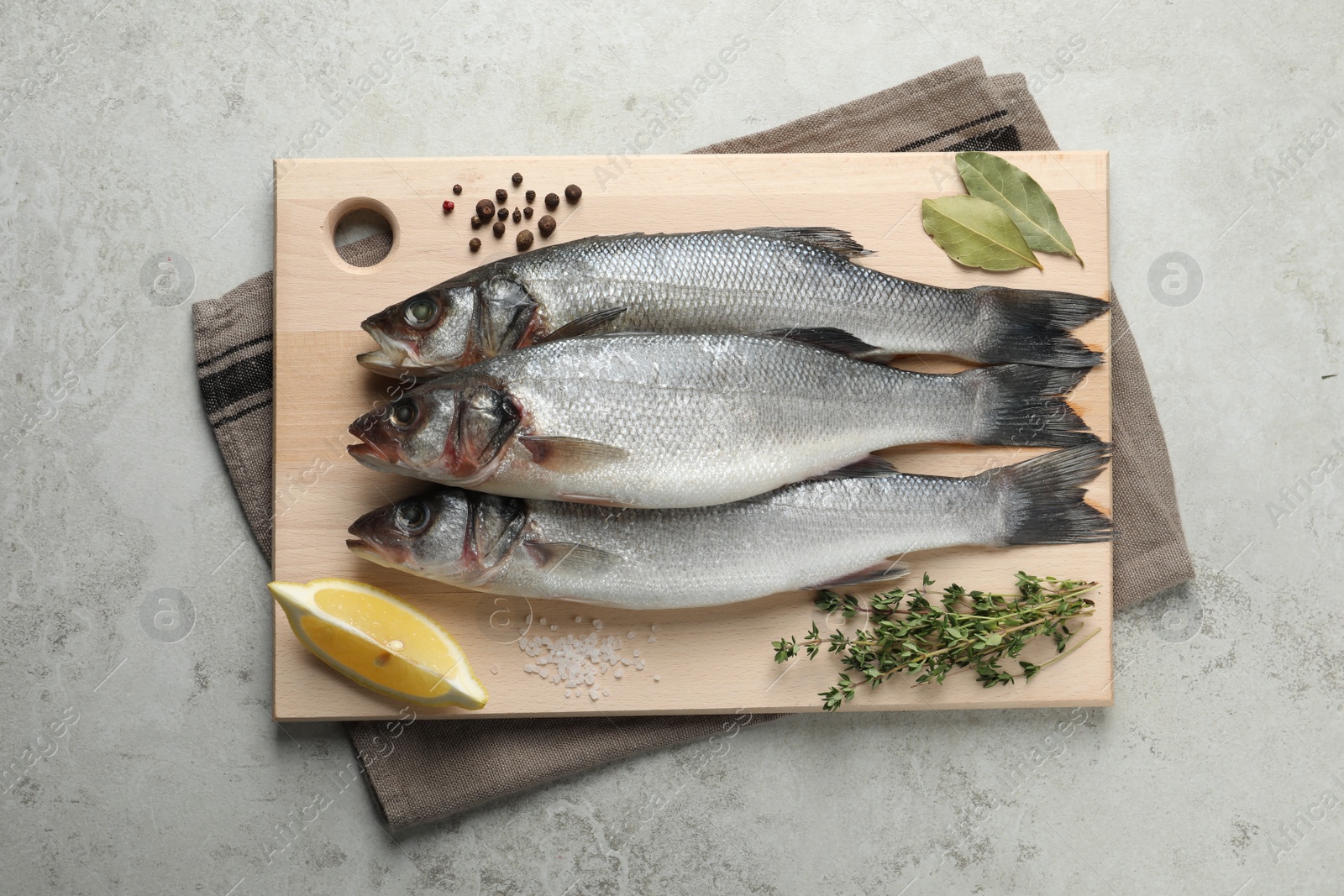 Photo of Tasty sea bass fish and spices on grey textured table, top view