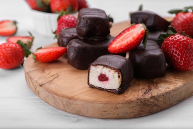 Photo of Delicious glazed curd snacks and fresh strawberries on white wooden table, closeup