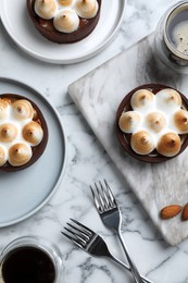 Photo of Delicious salted caramel chocolate tarts with meringue and coffee on white marble table, flat lay