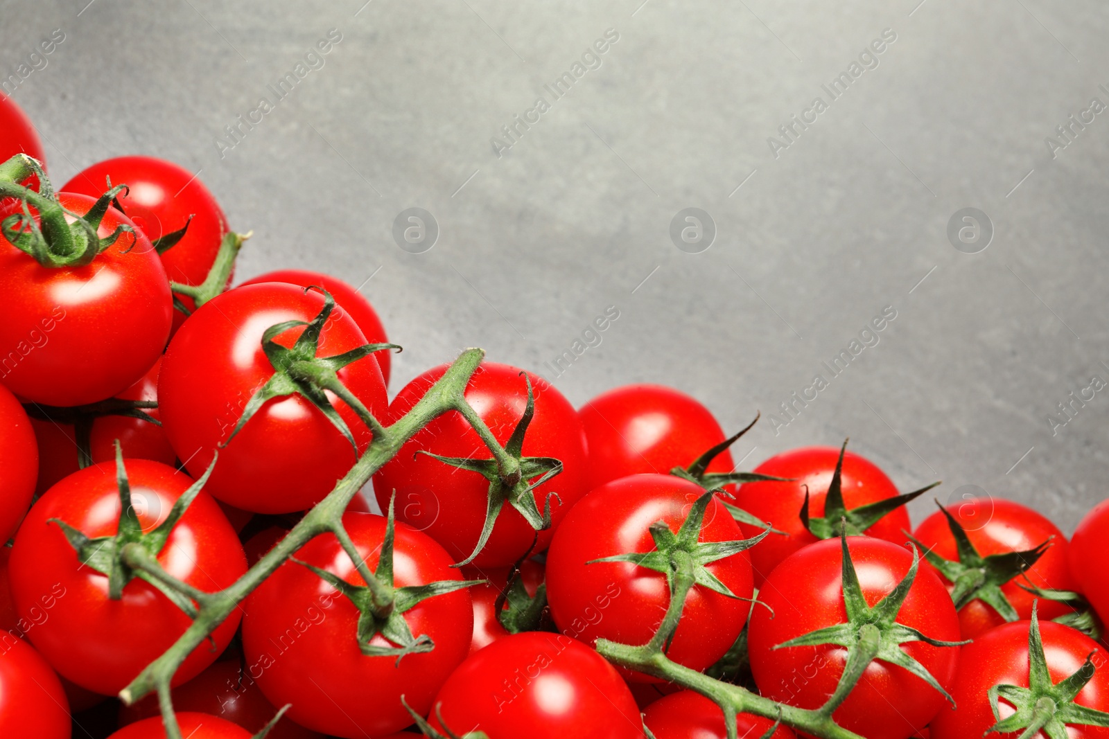 Photo of Heap of fresh cherry tomatoes on stone background, top view. Space for text