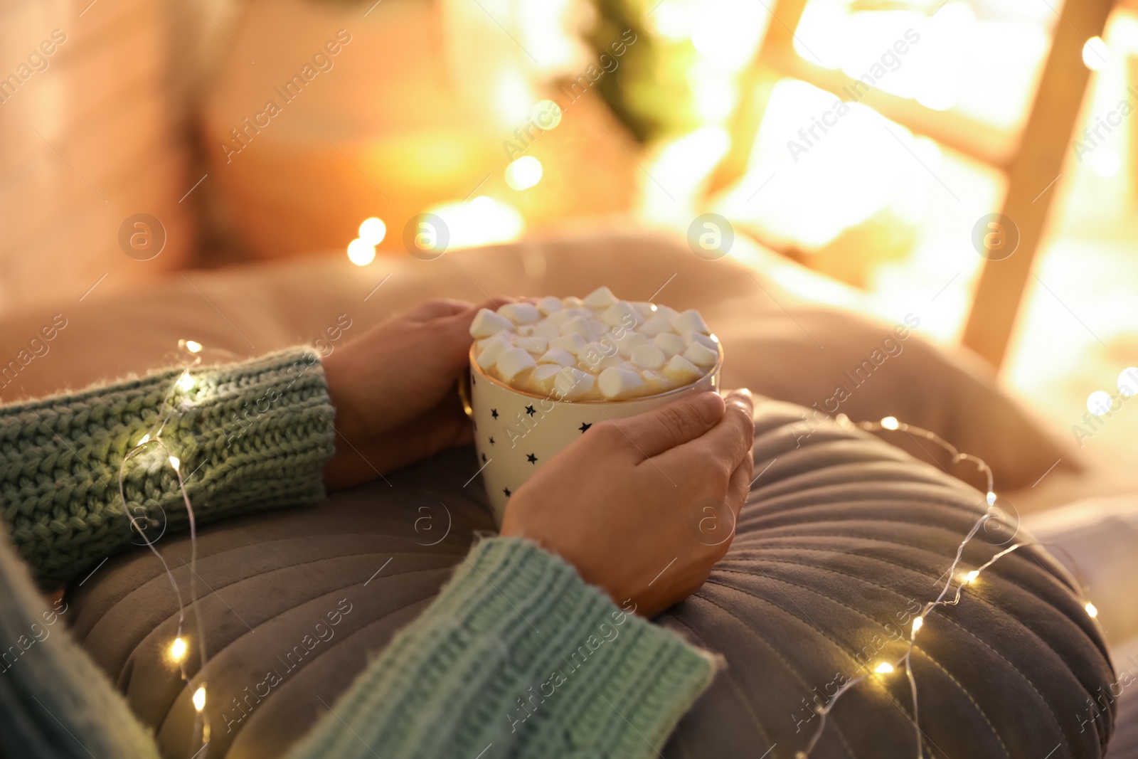 Photo of Woman holding cup of hot drink with marshmallows indoors, closeup. Magic Christmas atmosphere