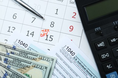 Photo of Tax day. Documents, dollar banknotes, pen and calculator on calendar with date reminder, flat lay