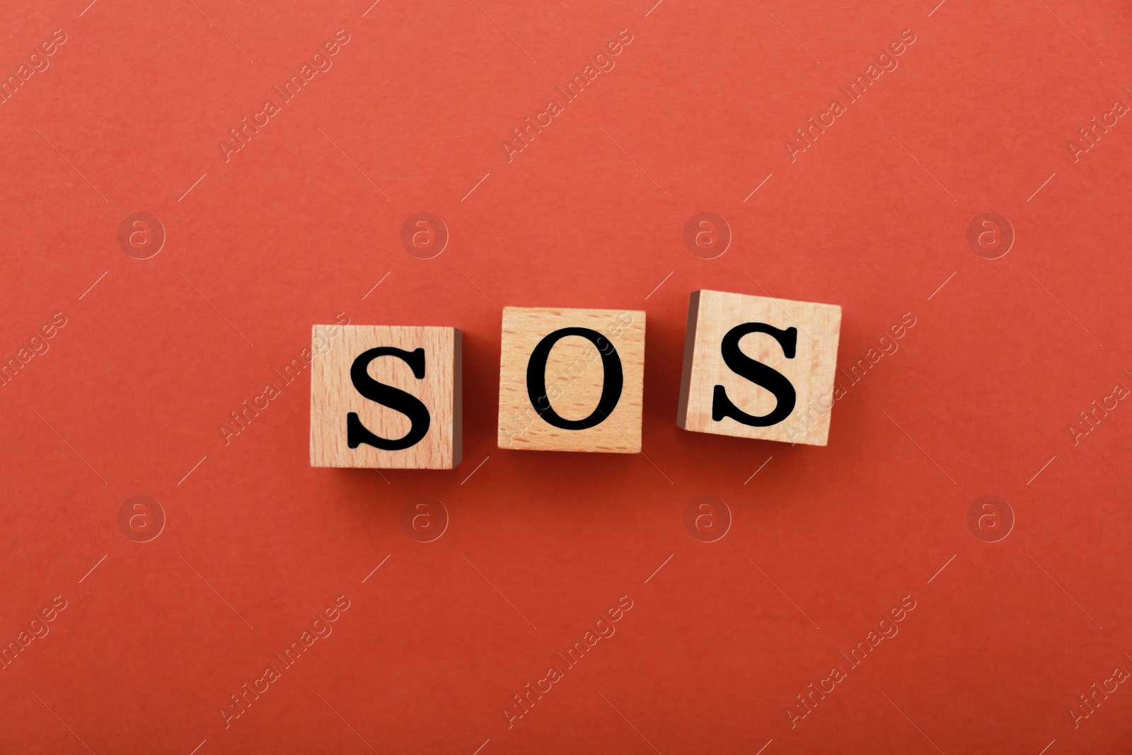 Photo of Abbreviation SOS made of wooden cubes on red background, top view