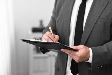 Notary writing notes in clipboard with pen indoors, closeup. Space for text