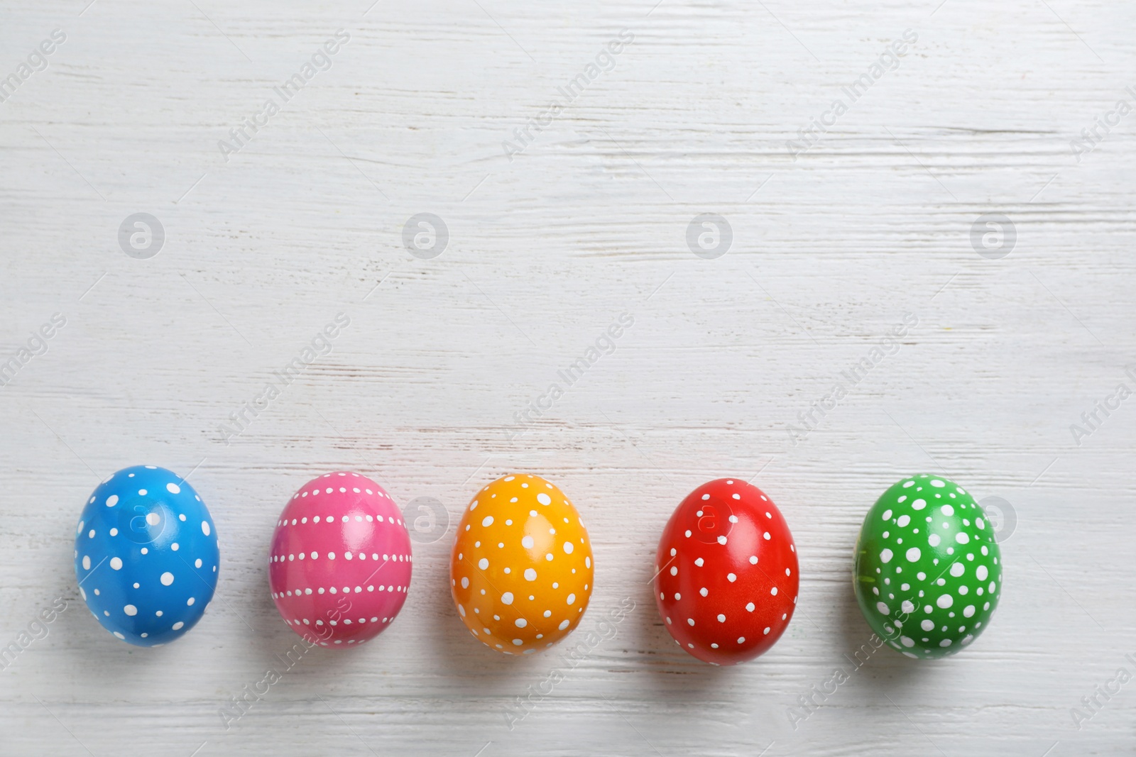 Photo of Decorated Easter eggs and space for text on wooden background, top view