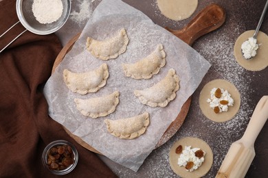 Process of making dumplings (varenyky) with cottage cheese. Raw dough and ingredients on brown table, flat lay