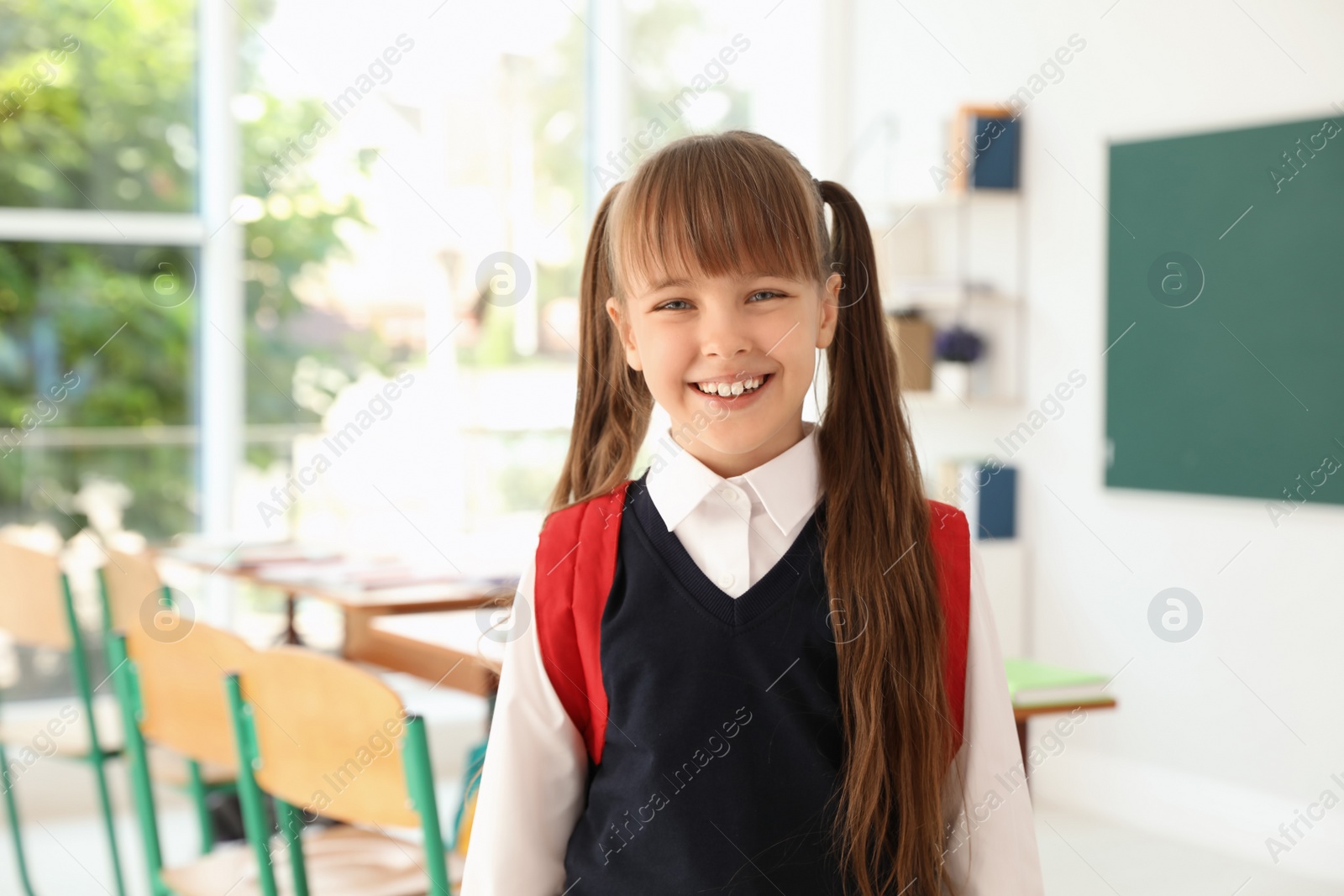 Photo of Little girl in classroom. Stylish school uniform