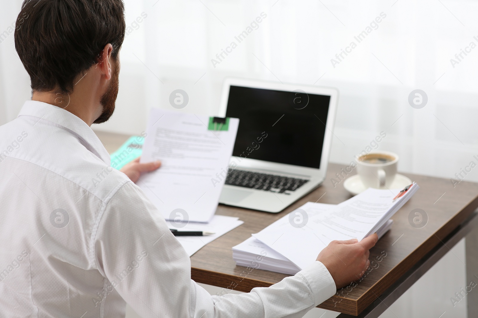 Photo of Businessman working with documents at table in office, back view