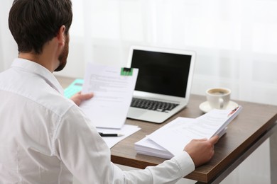 Photo of Businessman working with documents at table in office, back view