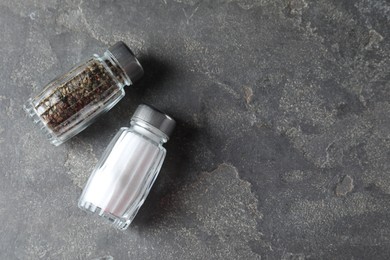 Photo of Salt and pepper shakers on grey textured table, top view. Space for text