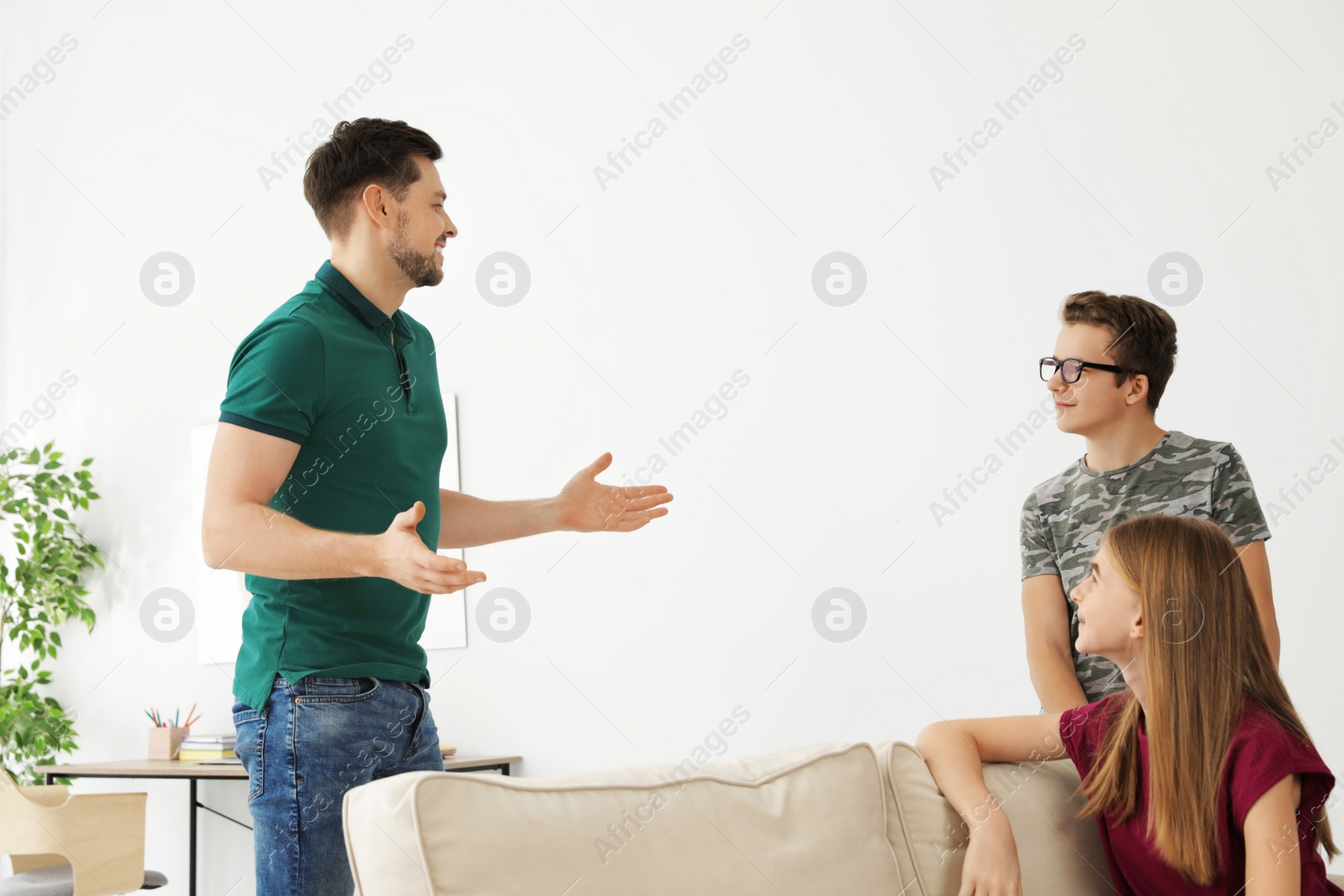 Photo of Father talking with his teenager son and daughter at home
