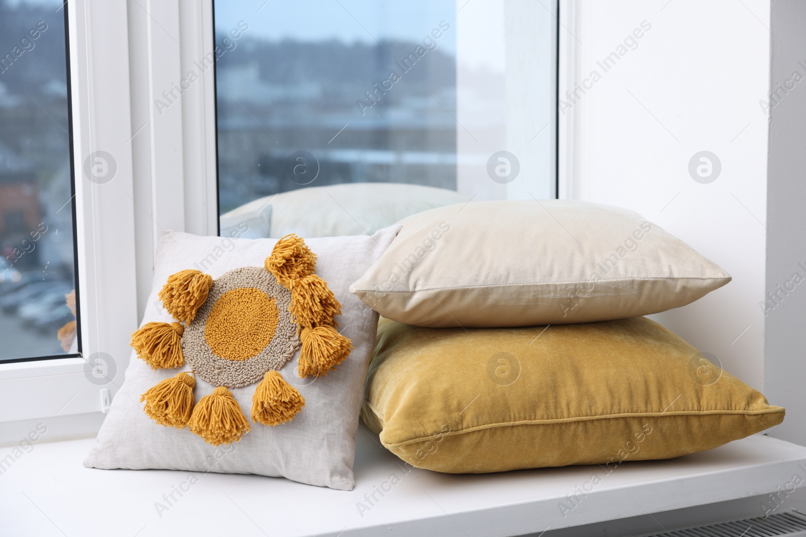 Photo of Different soft pillows on window sill indoors