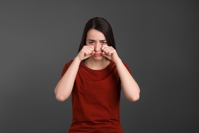 Portrait of emotional young woman on dark grey background. Personality concept