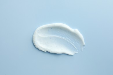 Photo of Sample of hand cream or scrub on light blue background, top view