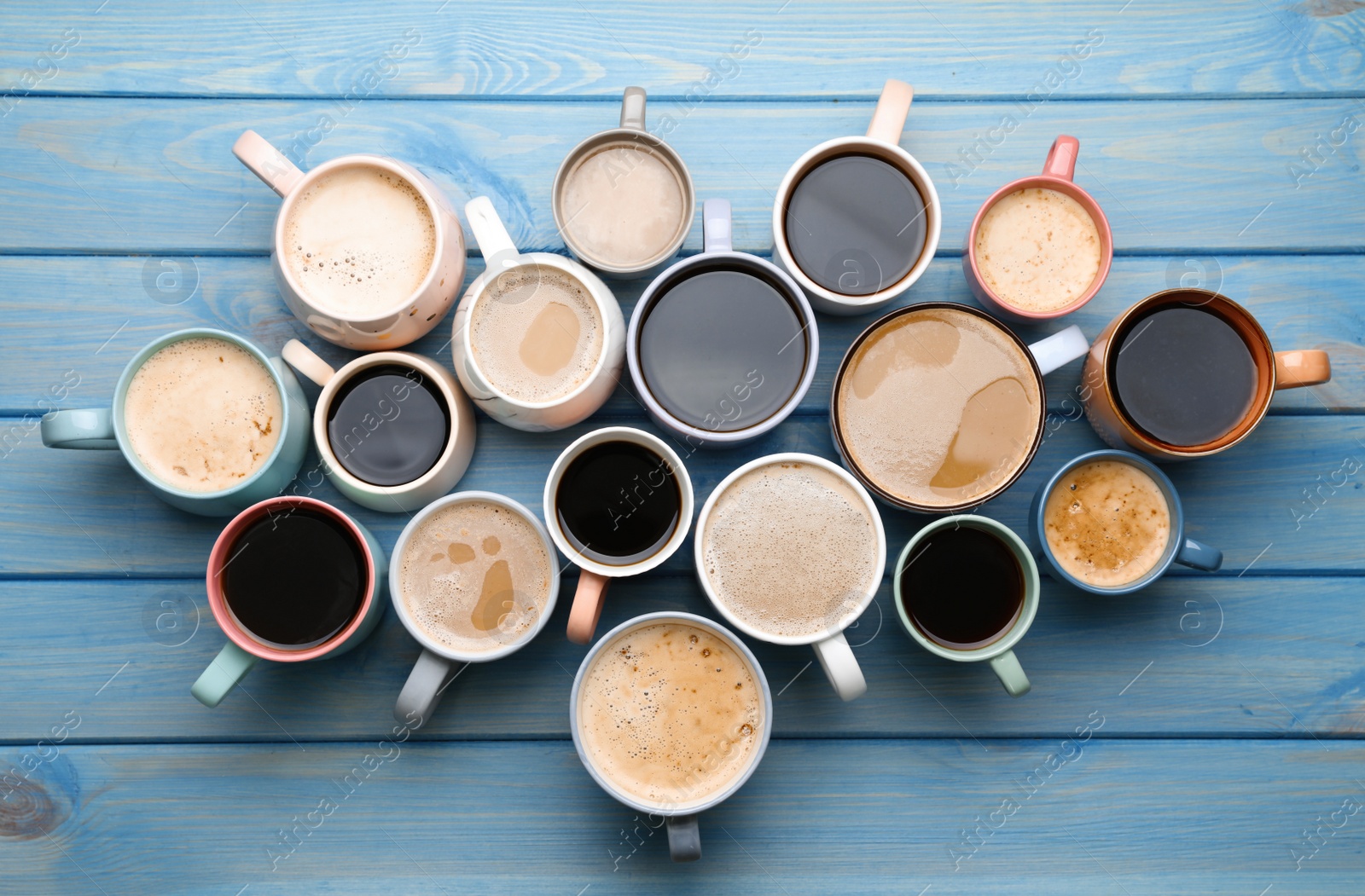 Photo of Many cups of different coffee drinks on light blue wooden table, flat lay