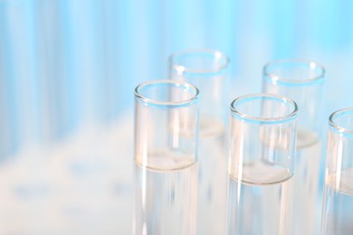 Photo of Laboratory analysis. Many glass test tubes on light blue background, closeup and space for text
