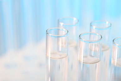 Laboratory analysis. Many glass test tubes on light blue background, closeup and space for text