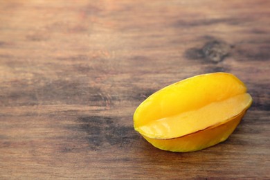 One delicious ripe carambola on wooden table, space for text