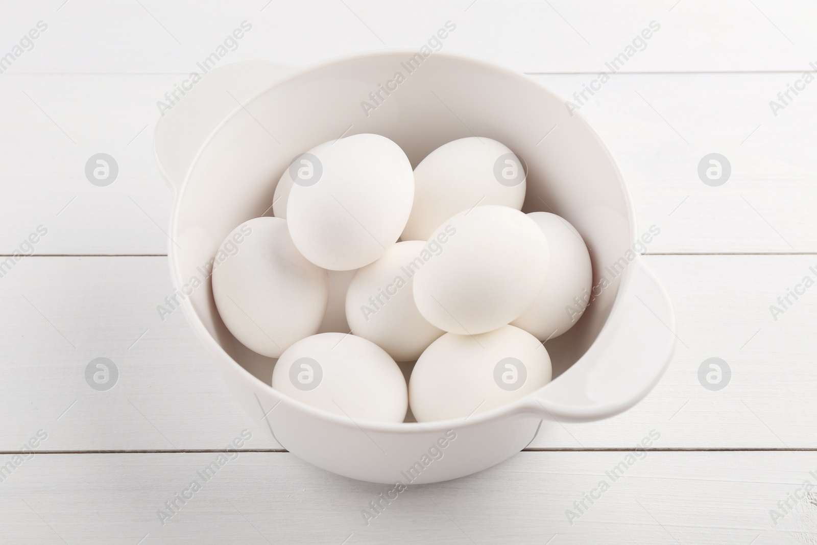 Photo of Boiled eggs in saucepan on white wooden table