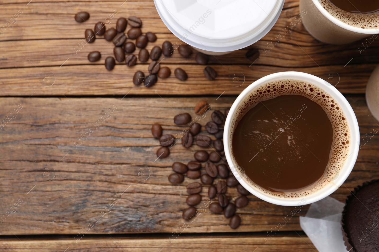 Photo of Coffee to go. Paper cups with tasty drink and beans on wooden table, flat lay. Space for text