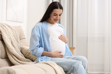 Photo of Happy pregnant woman on sofa at home