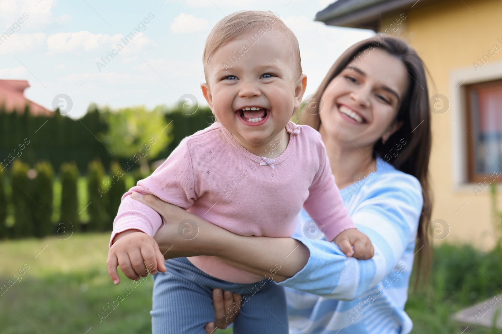 Photo of Happy mother playing with her cute baby at backyard on sunny day