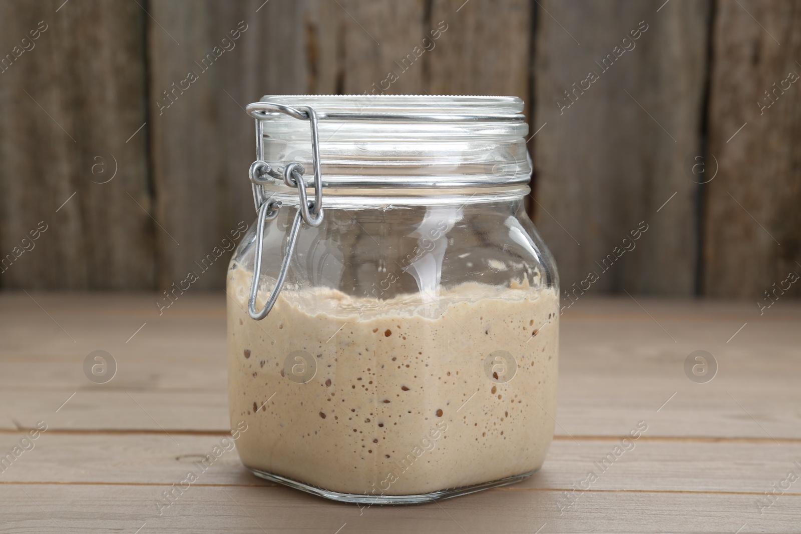 Photo of Leaven in glass jar on beige wooden table