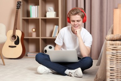 Online learning. Smiling teenage boy in headphones with laptop at home