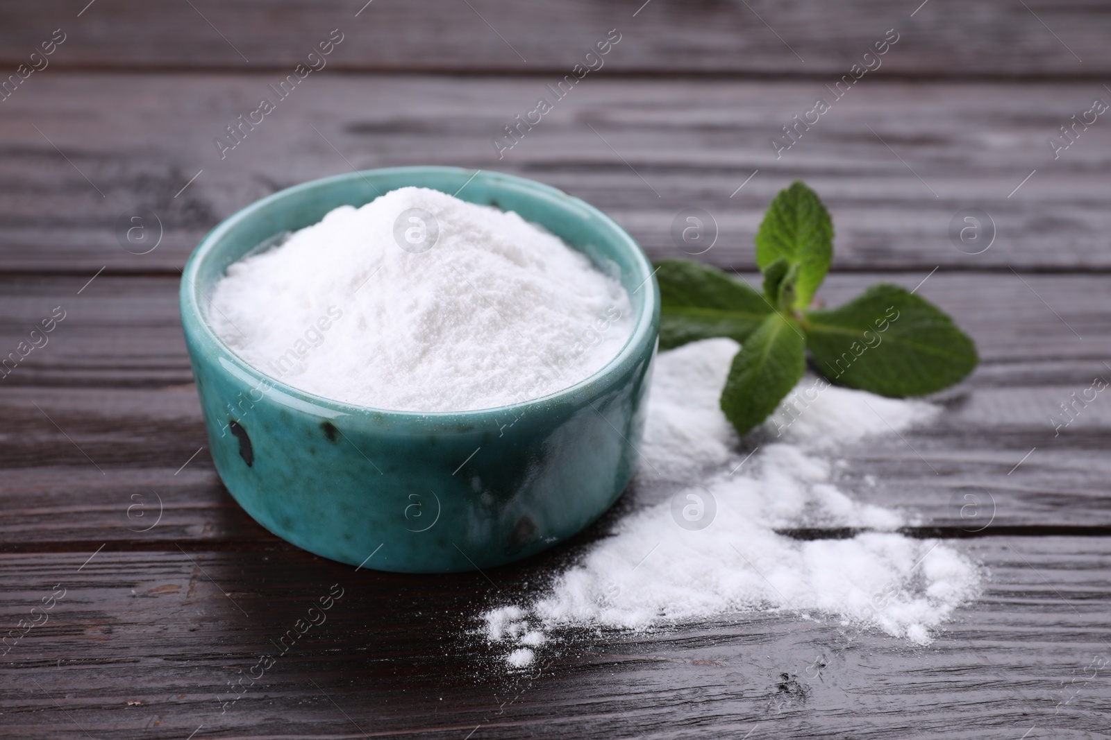 Photo of Sweet fructose powder and mint leaves on dark wooden table