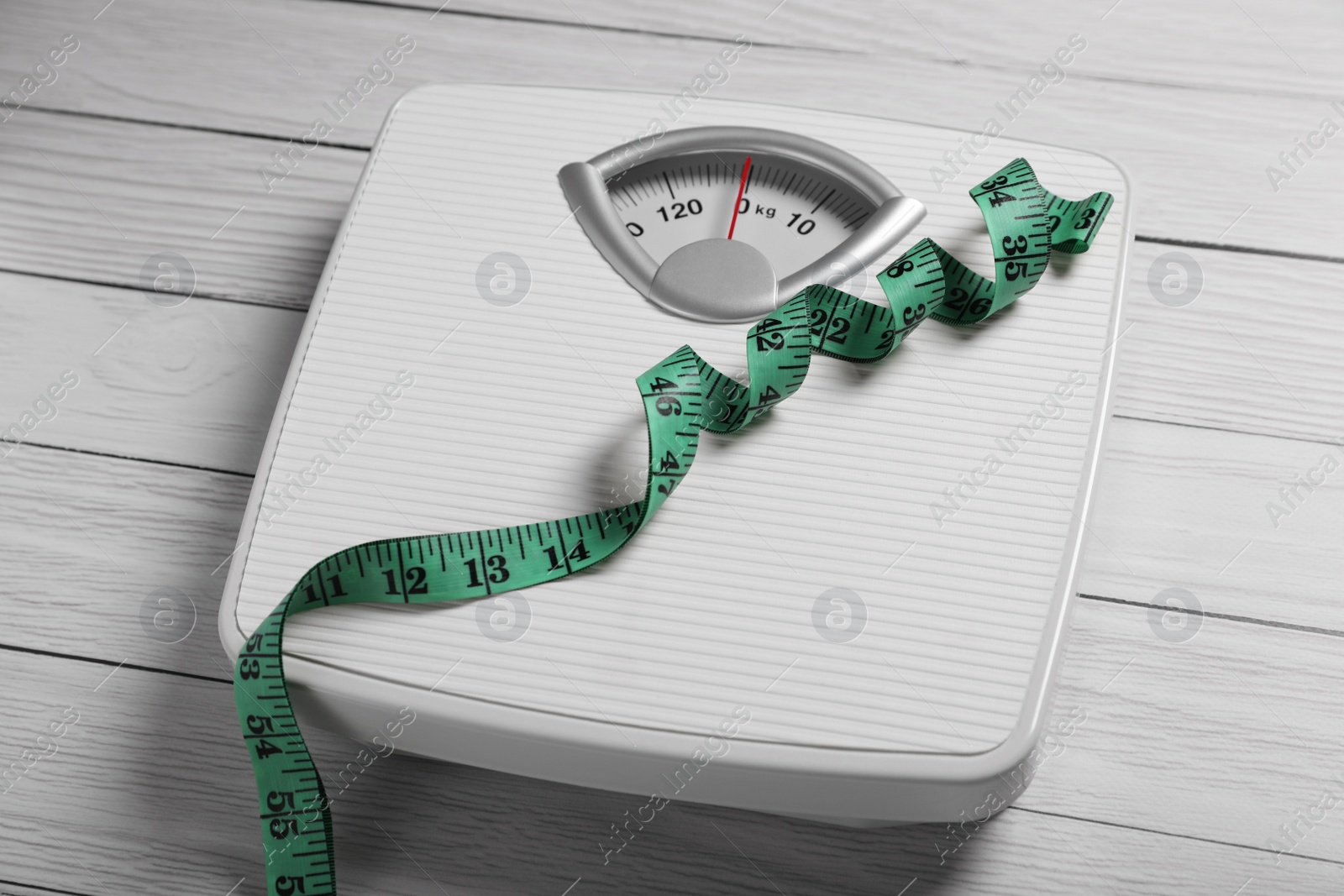 Photo of Scales with measuring tape on white wooden background. Weight loss concept