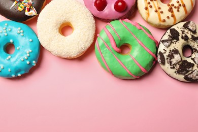 Different delicious glazed doughnuts on pink background, flat lay. Space for text