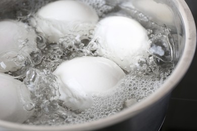 Chicken eggs boiling in saucepan, closeup view