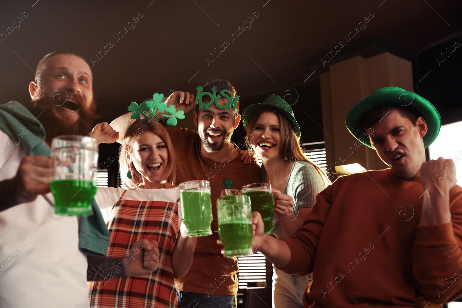 Photo of Group of friends with glasses of green beer in pub. St. Patrick's Day celebration