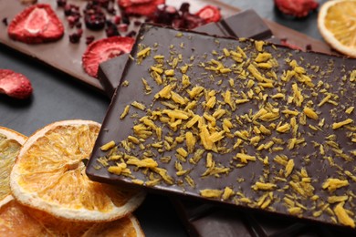 Photo of Different chocolate bars with freeze dried fruits on black table, closeup