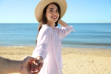 Happy young woman holding her husband's hand on beach near sea, closeup. Honeymoon trip