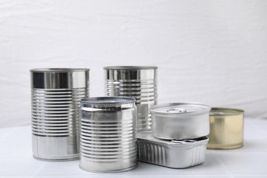 Photo of Many closed tin cans on white tiled table