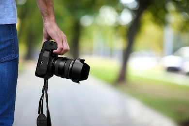 Photographer with professional camera in park, closeup