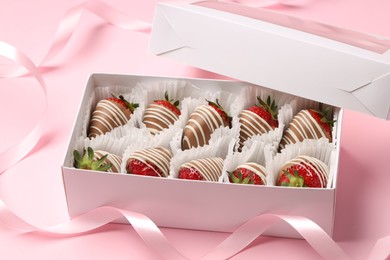 Box with delicious chocolate covered strawberries on pink background