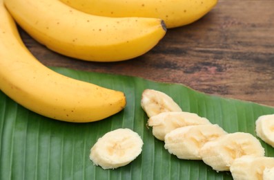 Photo of Delicious ripe bananas and fresh leaf on wooden table