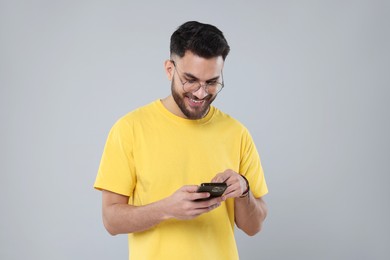 Photo of Happy young man using smartphone on grey background